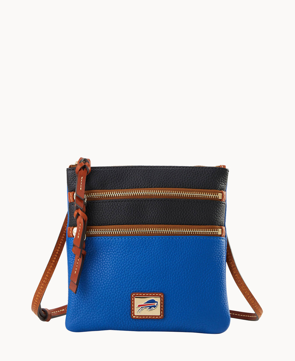 A small crossbody bag with a blue bottom half, black top half, two front zippered pockets, brown leather straps and trim, and a rectangular patch with a buffalo logo on the front.