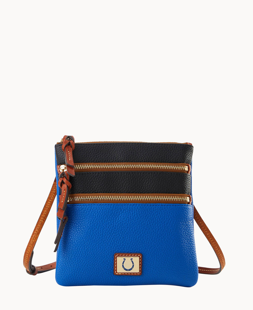 A small crossbody bag with a blue bottom half, black top half, brown leather strap, two front zippered pockets with gold zippers, and a gold emblem featuring a horseshoe on the front.