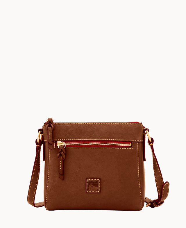 A small brown leather crossbody bag with a zippered front pocket, gold hardware, contrast stitching, and an adjustable strap, displayed against a plain white background.