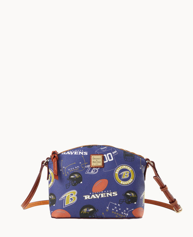A small crossbody bag with brown leather straps features a blue background decorated with Baltimore Ravens logos, football helmets, footballs, and RAVENS text.