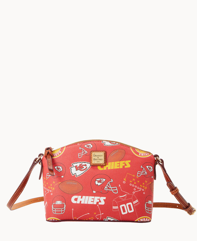 A red Dooney & Bourke crossbody bag featuring Kansas City Chiefs logos, footballs, helmets, and other football-themed graphics, with brown leather straps and gold-tone hardware.
