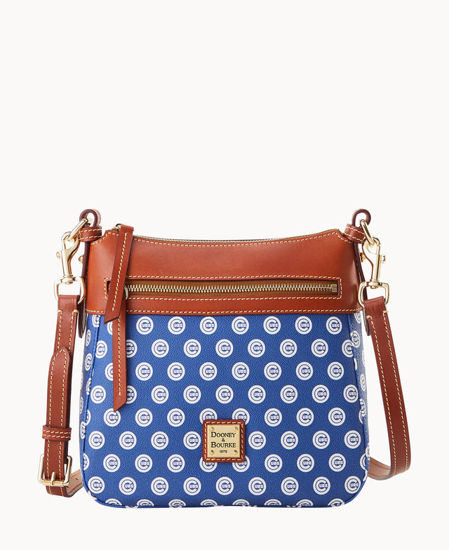 A blue crossbody purse with brown leather trim and gold hardware, featuring a repeating white Chicago Cubs logo pattern and a front zipper pocket. The Dooney & Bourke logo plate is displayed on the front.