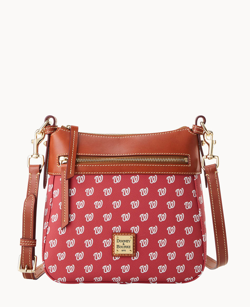 A red crossbody bag with brown leather trim and gold-tone hardware, featuring a repeating white W pattern and a front zip pocket. The Dooney & Bourke logo is displayed on a square patch in the center.
