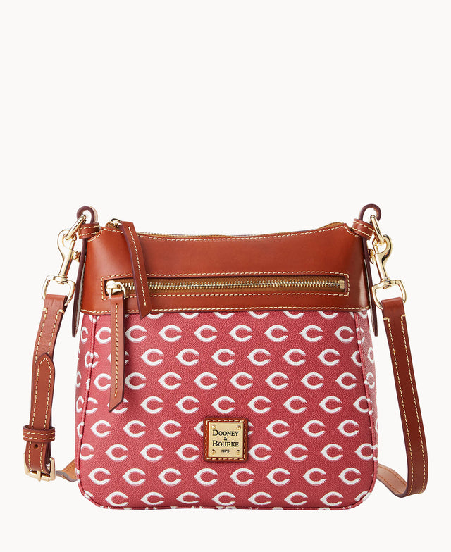 A red crossbody handbag with a brown leather trim, gold hardware, and adjustable strap. The bag features a repeating white “C†pattern and a front zip pocket with a gold Dooney & Bourke logo plate.