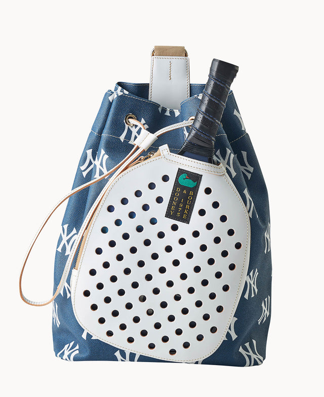 A blue and white drawstring bag with a repeating NY logo pattern holds a paddle and has a white perforated pocket on the front. The paddle handle sticks out from the top of the bag.