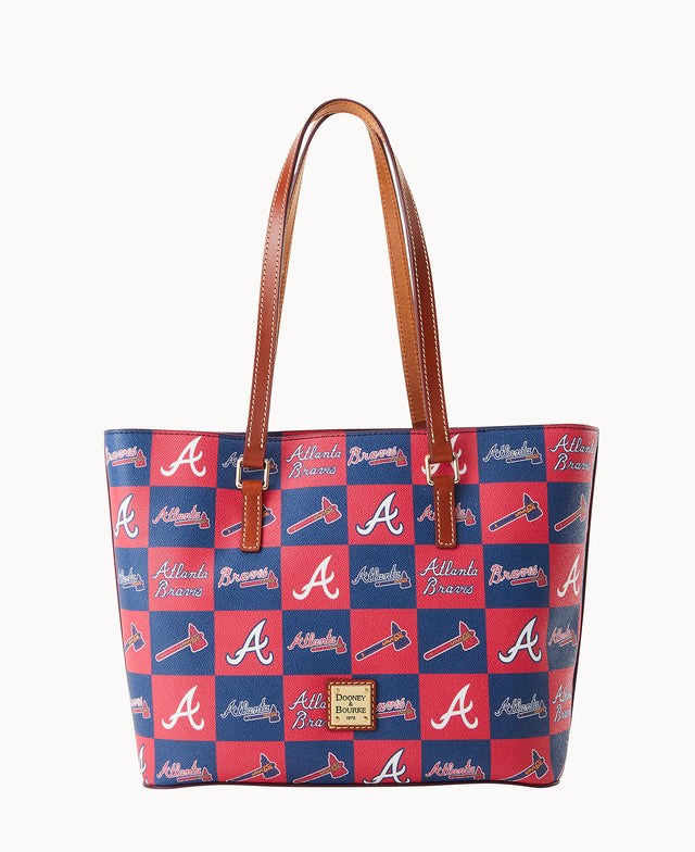 A tote bag with brown leather handles features a red and blue checkerboard pattern with Atlanta Braves logos, tomahawk symbols, and the words Atlanta Braves. A Dooney & Bourke label is on the front.