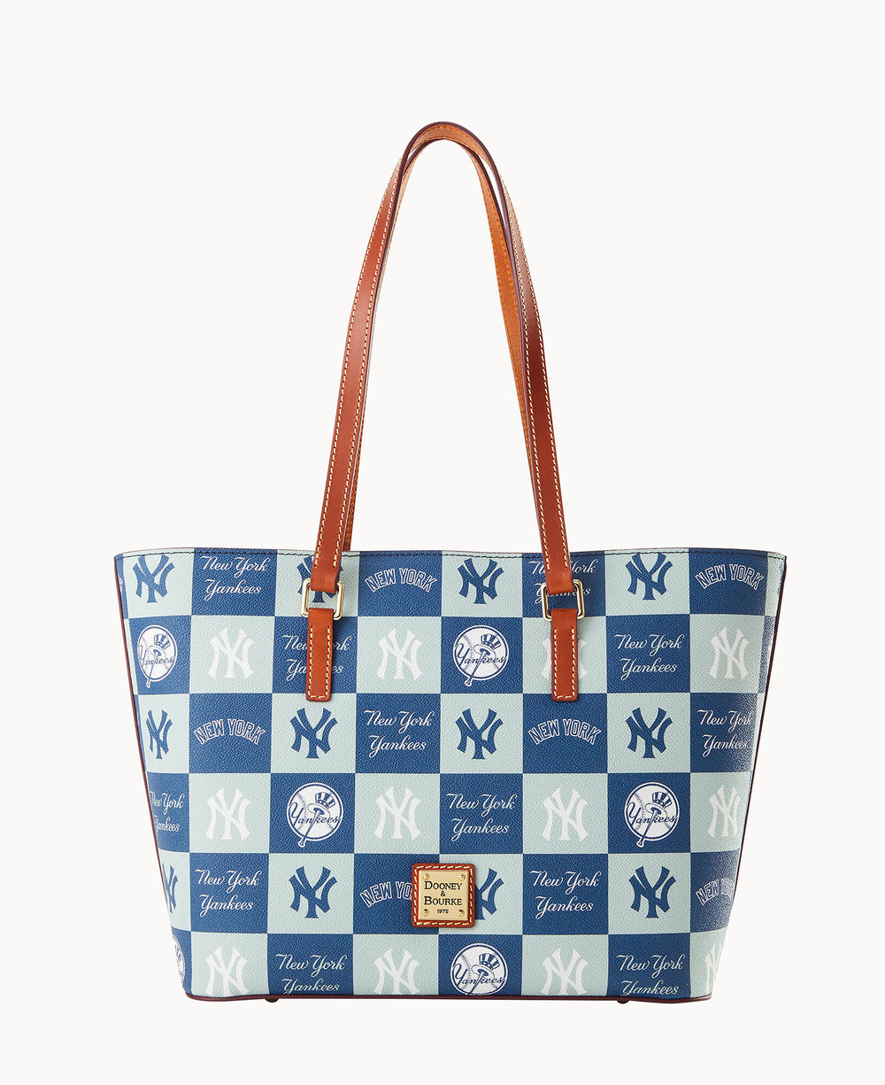 A tote bag with brown leather straps, featuring a blue and white checkered pattern decorated with New York Yankees logos and text.