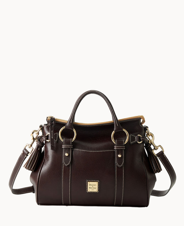 A dark brown leather handbag with gold hardware, double handles, a detachable shoulder strap, tassel accents, and a front logo plate, set against a white background.