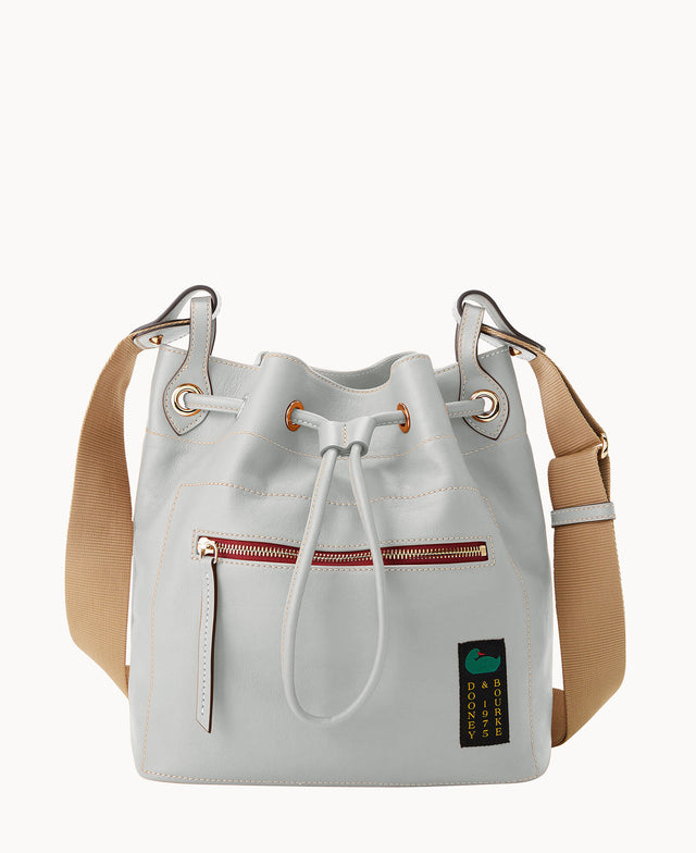 A light gray leather bucket bag with tan adjustable shoulder strap, front zipper pocket, drawstring closure, and a small black patch featuring text and a graphic in green and blue.