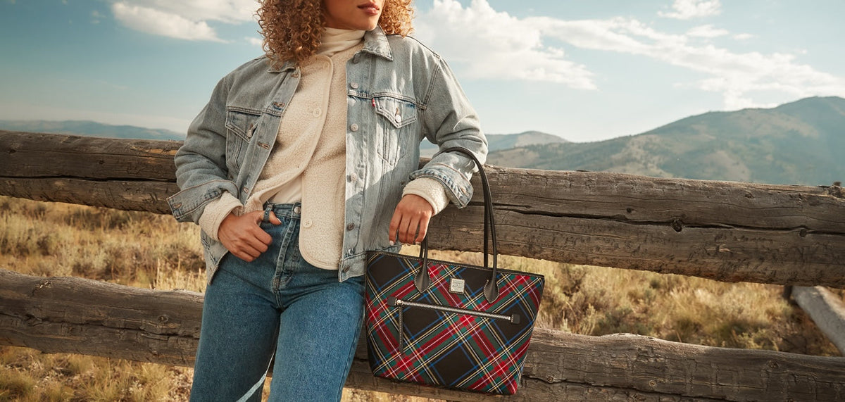 Woman standing in a field with a tartan Dooney & Bourke tote