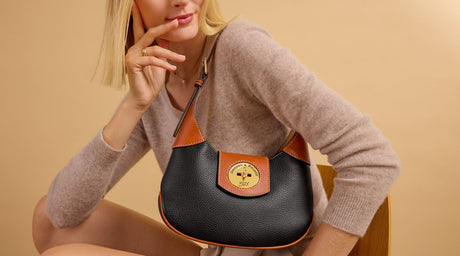 A woman is carrying a pebbled leather turnlock hobo.