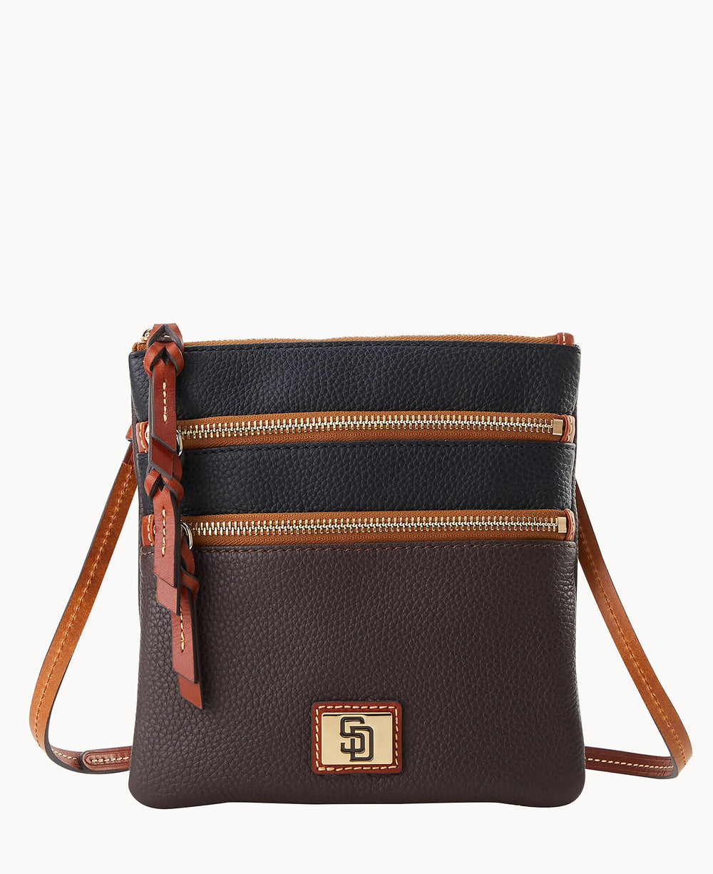 A small, crossbody leather purse with two zippered pockets on the front, featuring a brown body, dark upper section, tan trim, and a gold logo plate near the bottom center.