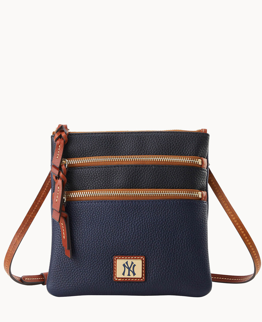 A navy blue leather crossbody bag with brown trim, two front zippered pockets, a long brown strap, and a New York Yankees logo patch on the front.