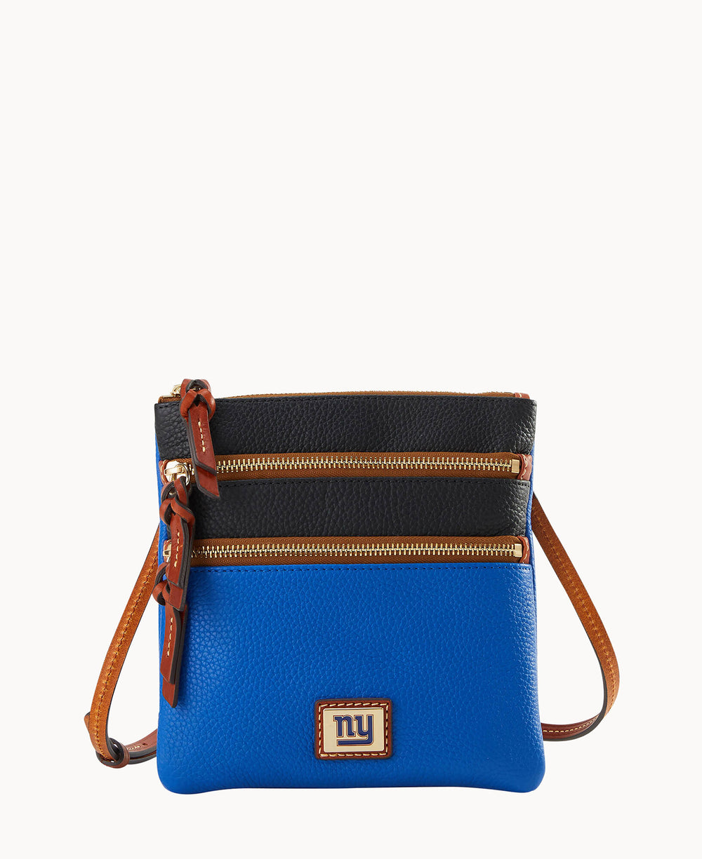 A crossbody bag with a blue bottom, black top, brown trim, two horizontal gold zippers, and a small NY logo patch on the front.