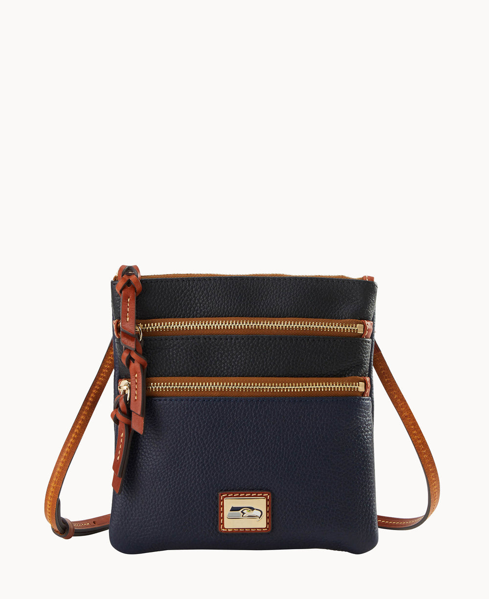 A small navy blue leather crossbody bag with two front zippered pockets, brown leather trim, an adjustable strap, and a gold logo plate on the front.