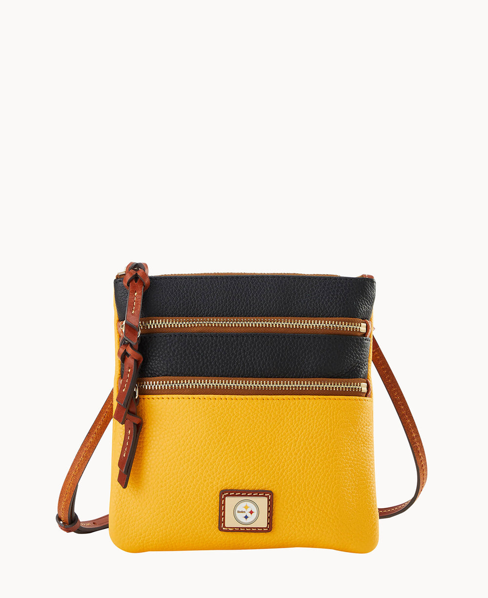 A small crossbody bag with a yellow bottom, black top, two gold zippered compartments, brown leather strap, and a rectangular logo patch on the front.