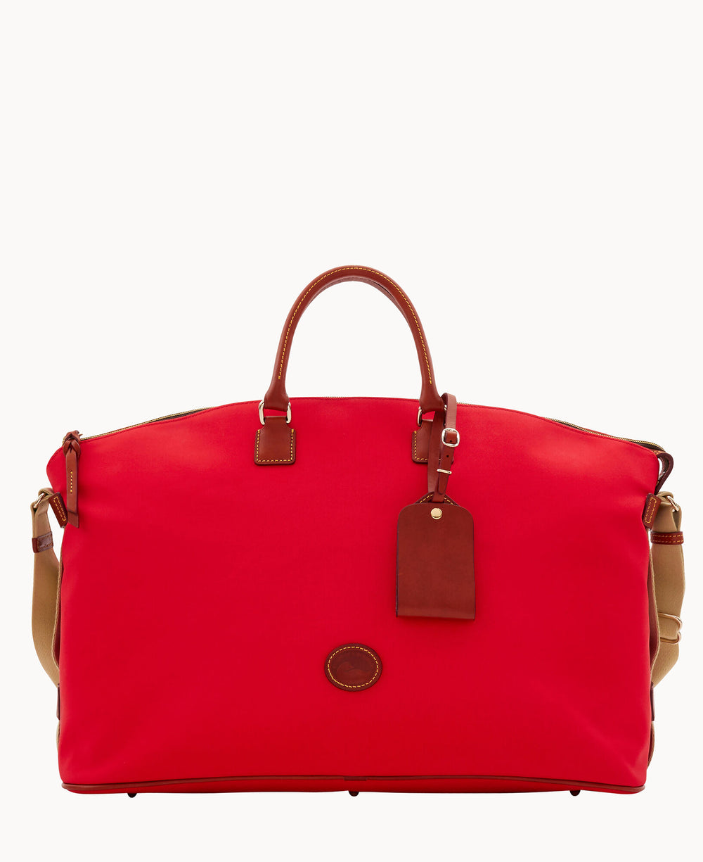 A large red travel duffel bag with brown leather handles, a matching leather luggage tag, and tan shoulder straps, displayed against a plain white background.