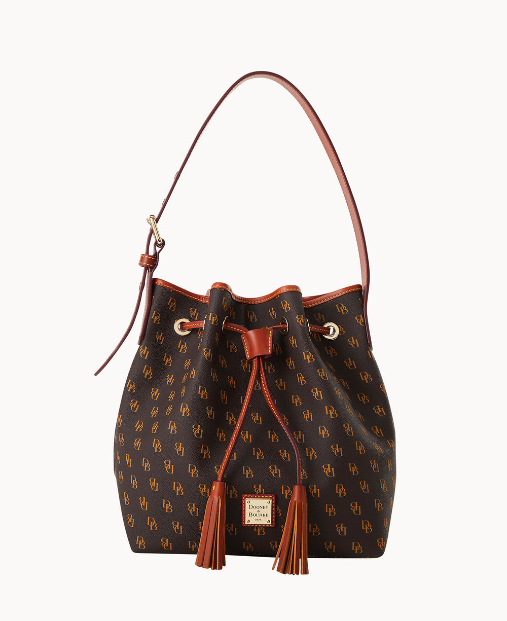 A brown bucket bag with a drawstring closure, leather trim, and tassels. The bag features an all-over monogram print and a single shoulder strap with gold-tone hardware.