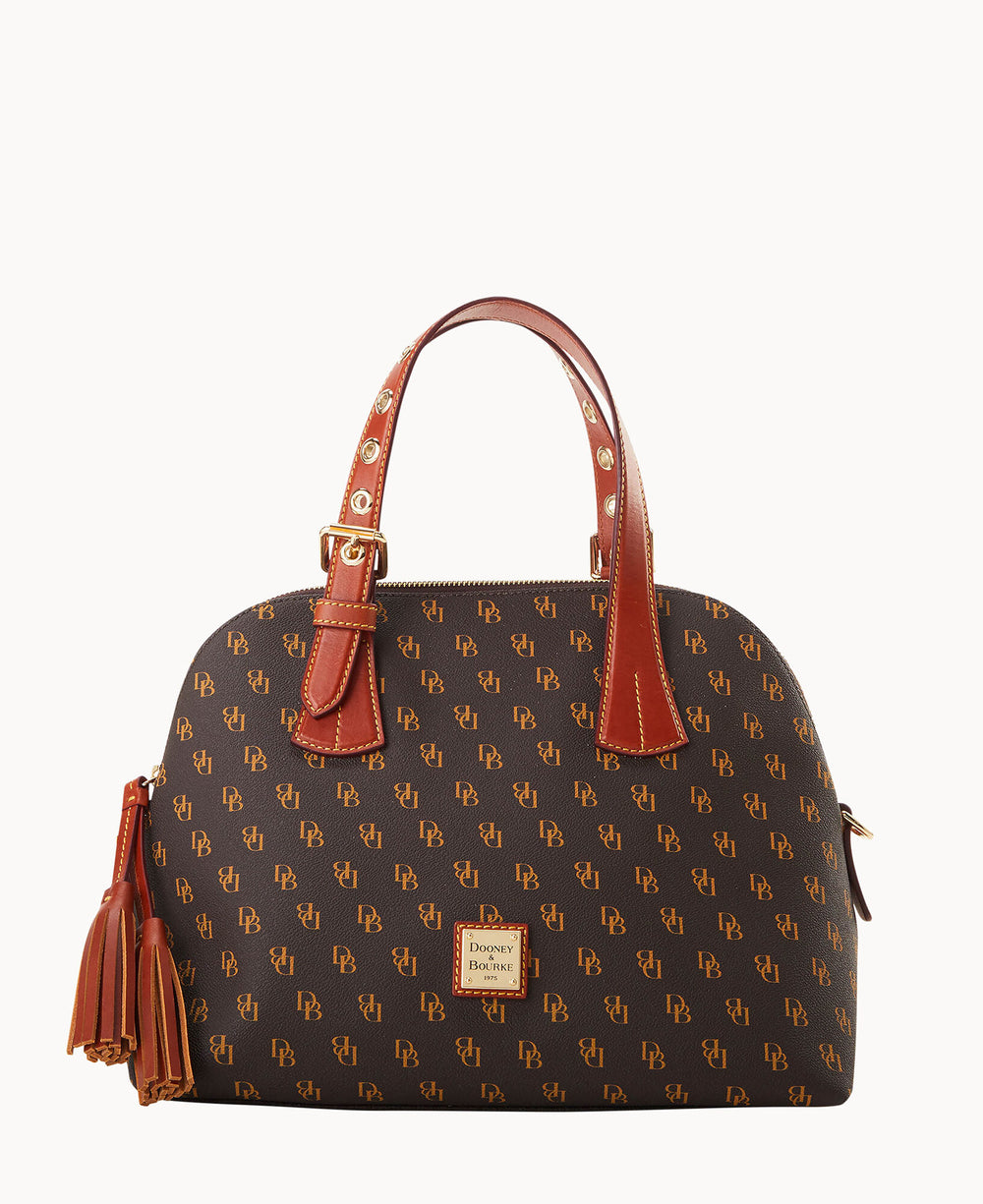 A brown Dooney & Bourke handbag with tan logo print, red-brown leather handles, gold-tone hardware, a front logo plate, and a tassel accent on the side.