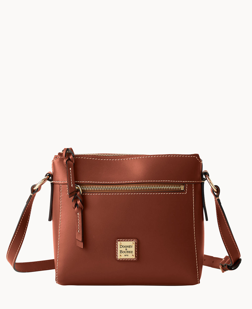 A brown leather crossbody bag with white stitching, a front zip pocket, a gold zipper, a decorative leather tassel, and a small Dooney & Bourke logo patch on the front.