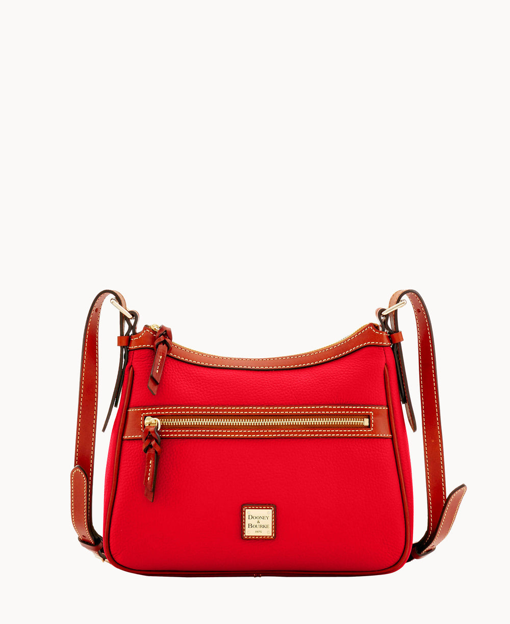A small red shoulder bag with brown leather trim, a front zip pocket, gold zipper details, adjustable leather strap, and a rectangular Dooney & Bourke logo patch on the front.