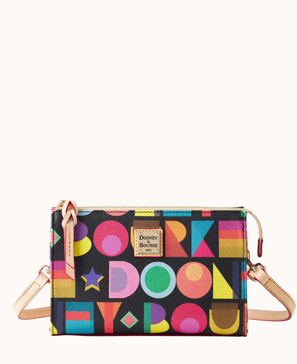 A small crossbody bag with colorful geometric shapes and letters on a black background, featuring a tan leather strap and trim, and a Dooney & Bourke logo patch on the front.