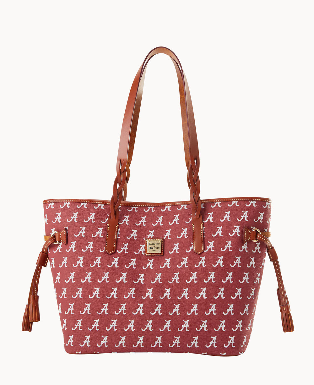 A maroon tote bag with brown handles and tassels, featuring a repeating white script A pattern. The bag has gold hardware and a small logo plate on the front.