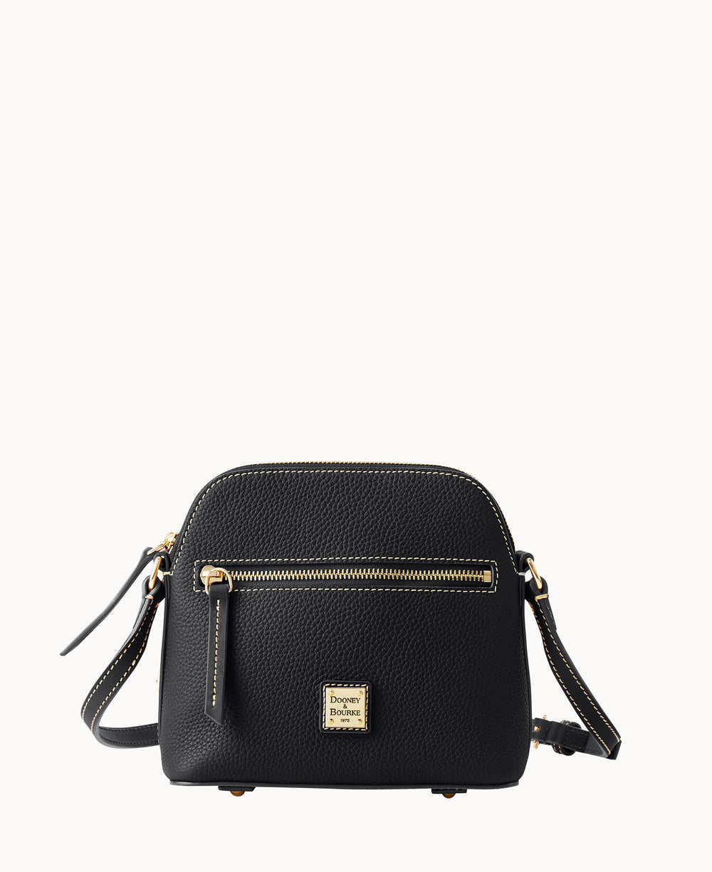 A small black leather crossbody bag with gold-tone hardware, an exterior zip pocket, and a square Dooney & Bourke logo patch on the front. The bag has a textured finish and an adjustable strap.