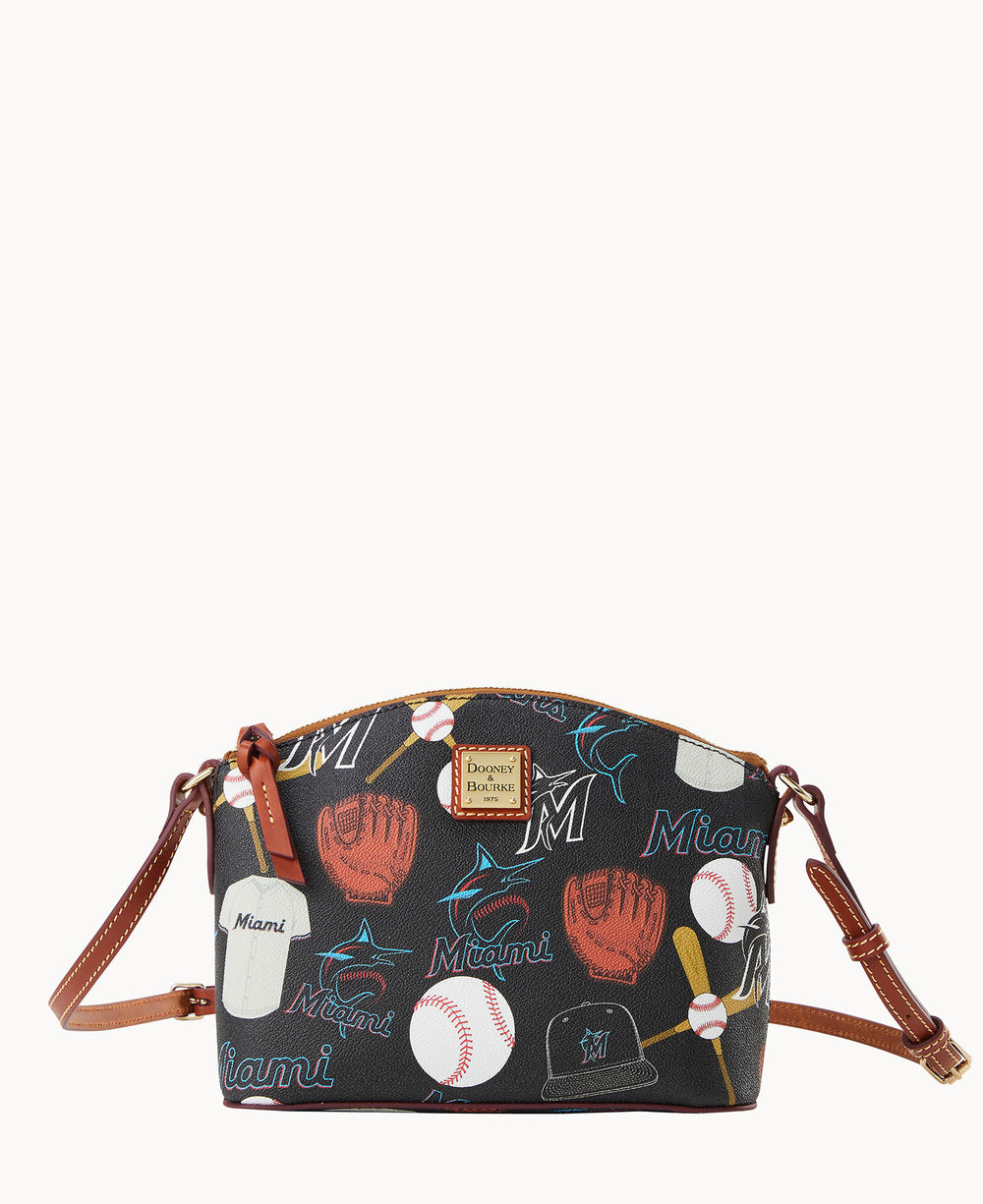 A small crossbody bag with brown leather straps featuring a baseball-themed Miami Marlins print, including gloves, bats, balls, caps, and the word Miami on a dark background.