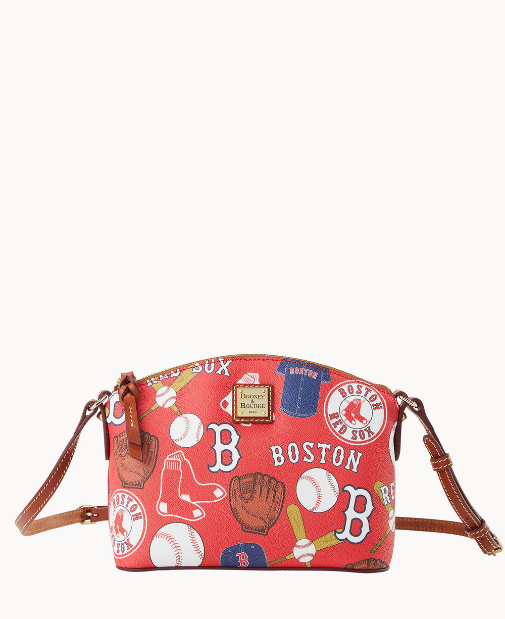 A red crossbody bag with brown leather straps featuring Boston Red Sox-themed prints, including logos, baseballs, gloves, socks, and hats. The bag has a gold Dooney & Bourke logo plate on the front.