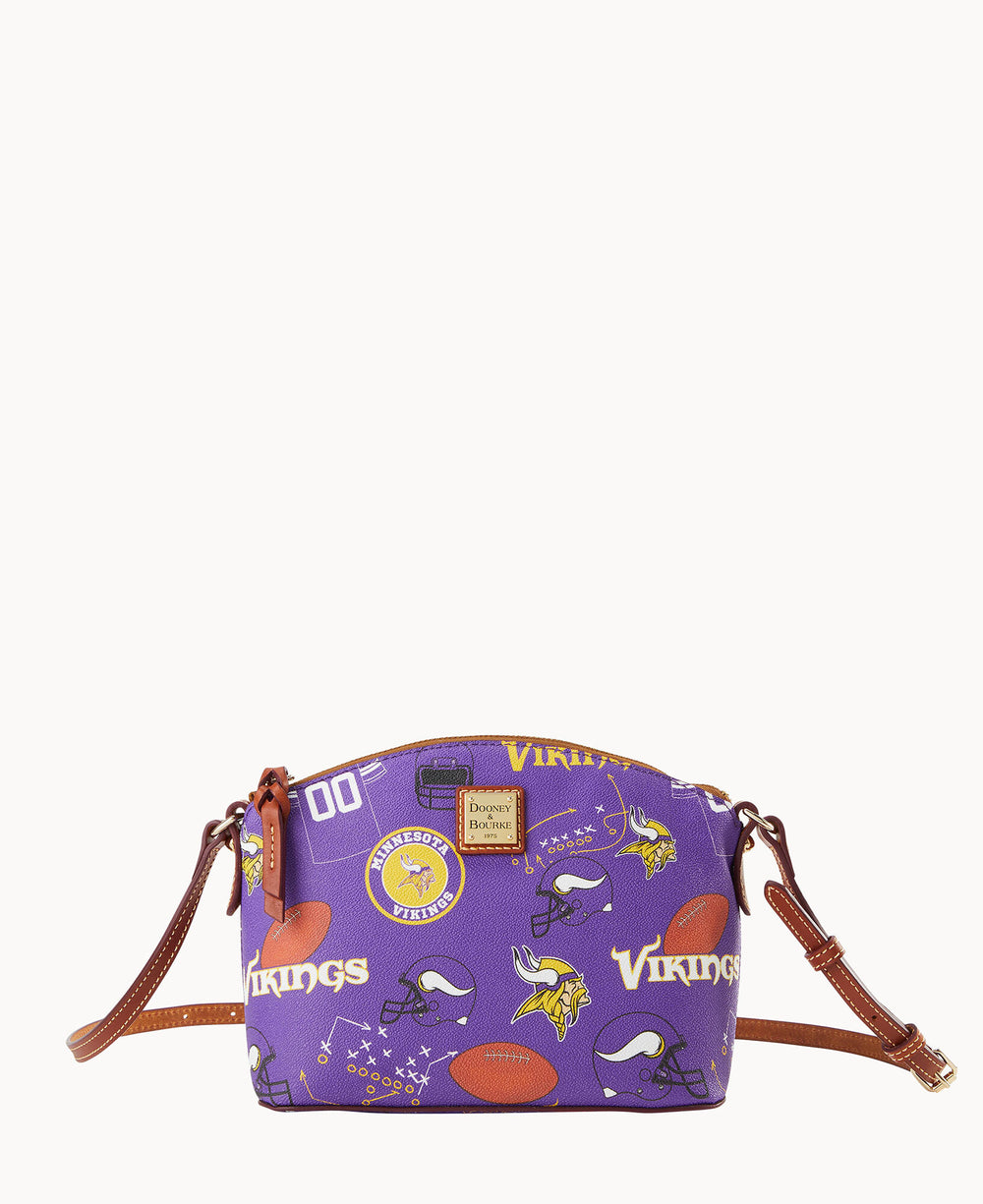 A small purple crossbody bag with brown straps features Minnesota Vikings football-themed graphics, including helmets, logos, footballs, and the word Vikings in yellow and white lettering.