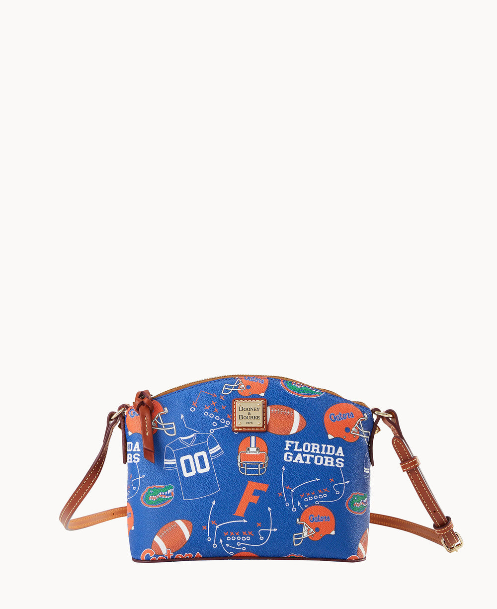 A small crossbody bag with brown leather straps and trim, featuring a blue background with Florida Gators football-themed graphics, including helmets, footballs, and team logos.