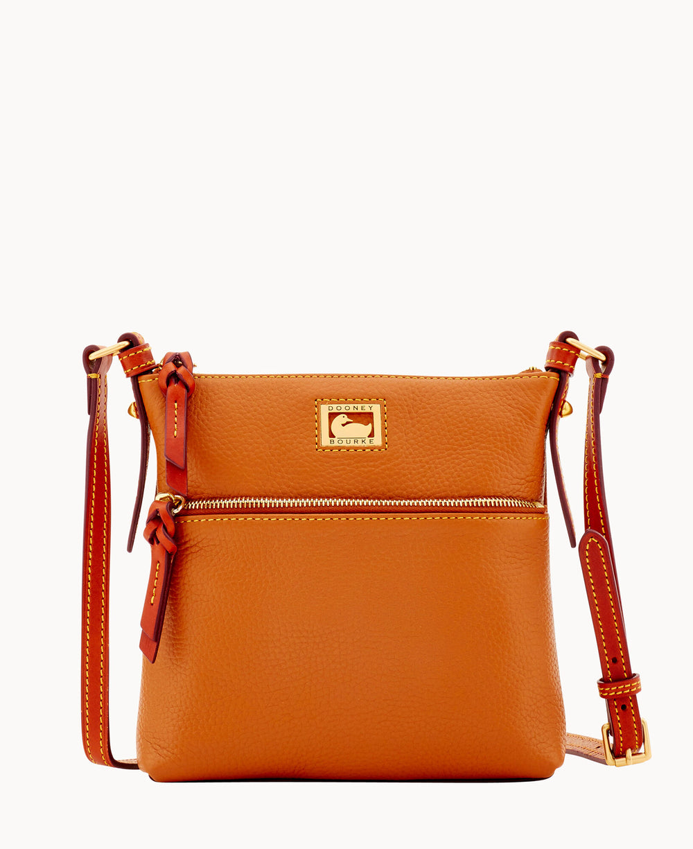 A medium-sized, orange leather crossbody bag with gold hardware, an exterior zip pocket, adjustable strap, and a rectangular metal logo plate on the front.