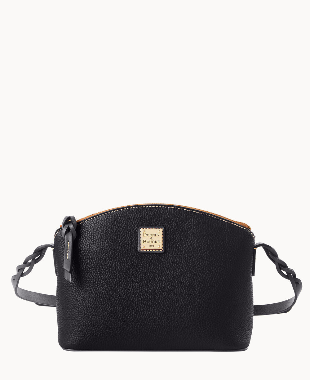 A black leather crossbody bag with a textured surface, gold Dooney & Bourke logo plate on the front, a zippered top, and braided strap details on each side.