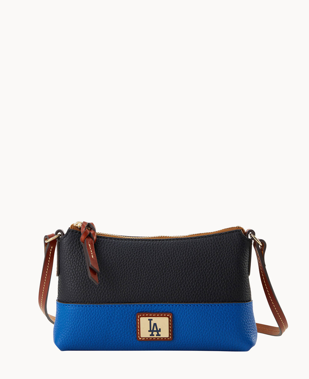 A small crossbody bag with a black upper half and a blue lower half, featuring a brown leather strap and a patch with LA on the front. The bag has a zipper closure with a brown pull tab.