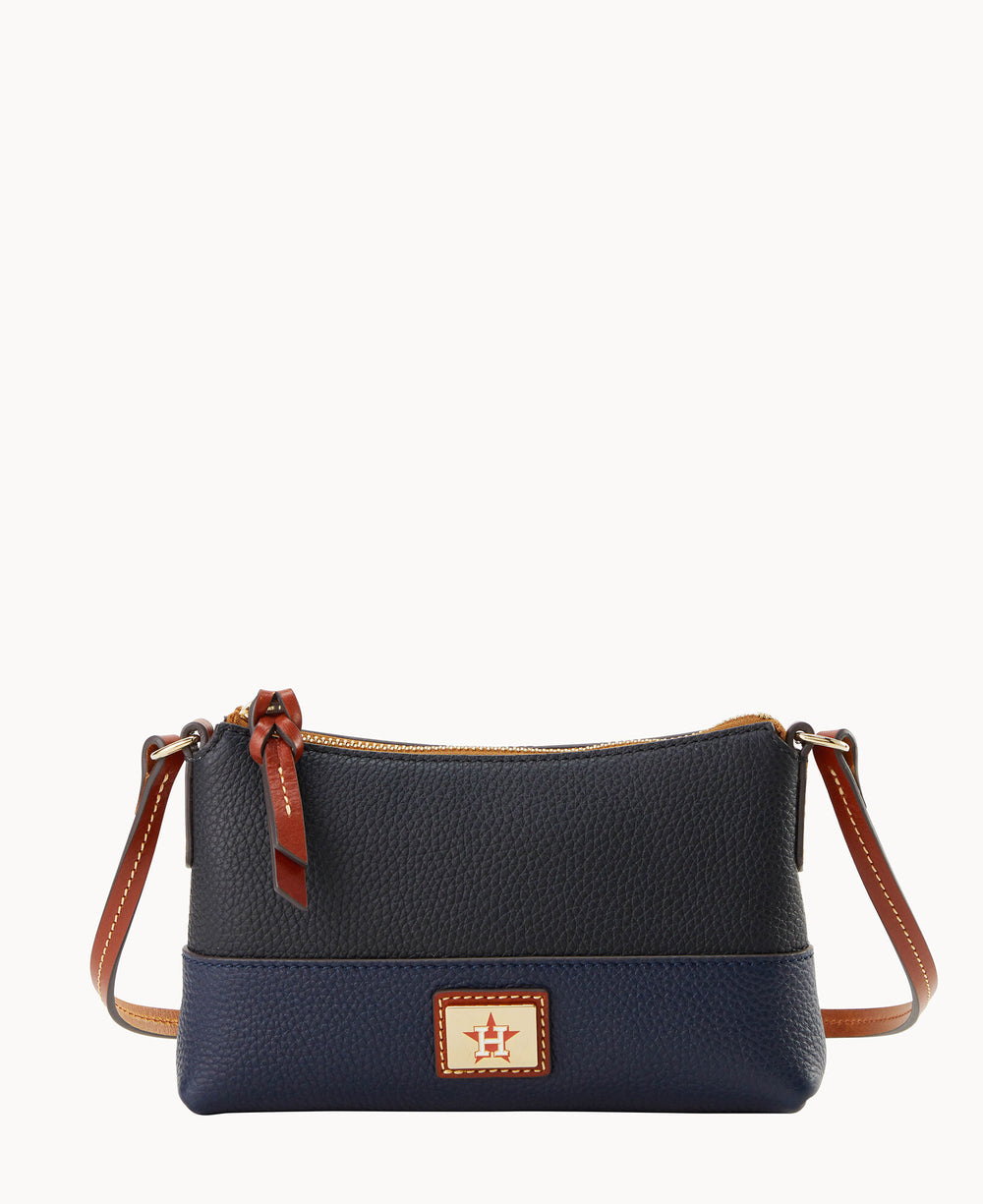 A small navy blue leather crossbody bag with brown leather accents, a top zipper closure, and a rectangular gold and red logo plate on the front. The bag has a long brown strap with white stitching.
