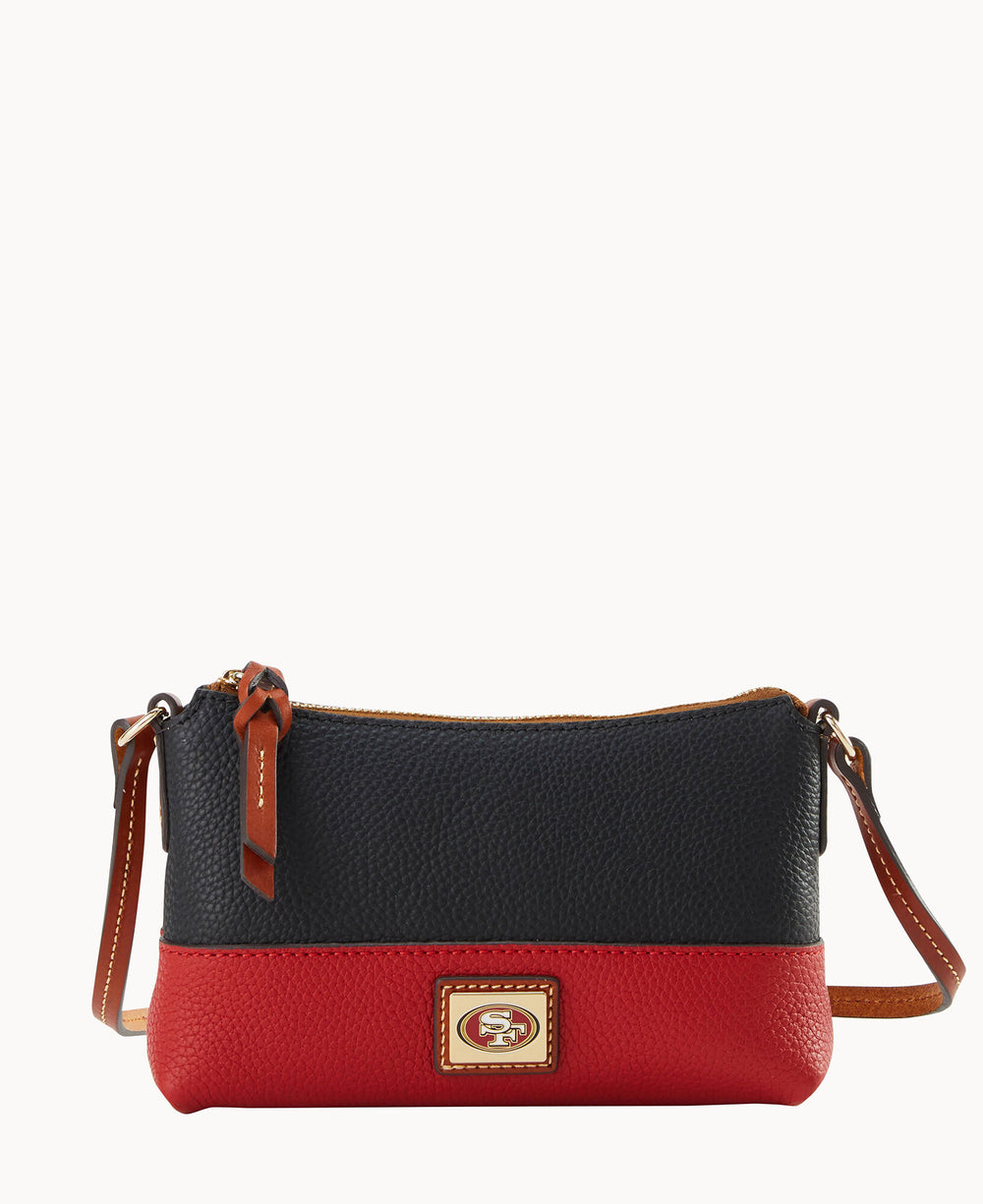 A small crossbody purse with a black top, red bottom, brown leather strap, and zipper. The front features a gold and red emblem with the San Francisco 49ers logo.