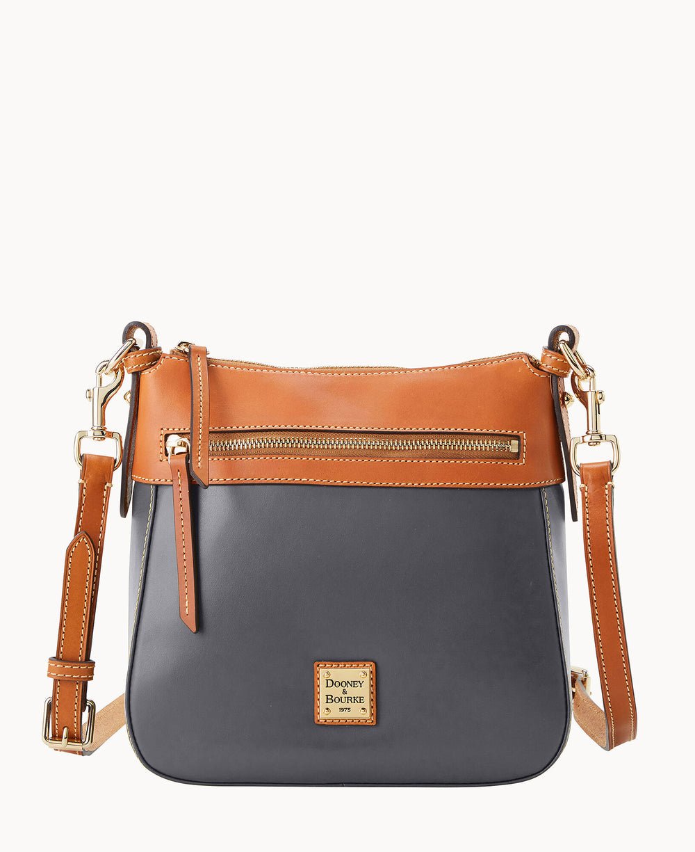 A crossbody bag with a dark gray body, brown leather trim, gold zipper and hardware, adjustable strap, and a small Dooney & Bourke logo patch on the front.