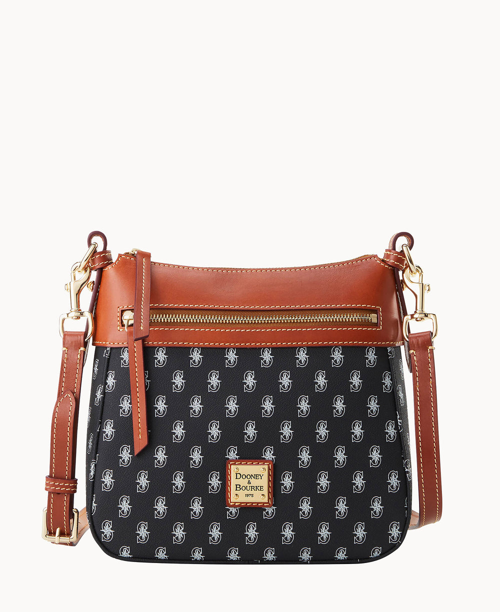 A black Dooney & Bourke crossbody bag with brown leather trim, a front zipper pocket, gold hardware, and a repeating white logo pattern. The bag has an adjustable strap and a gold brand label on the front.