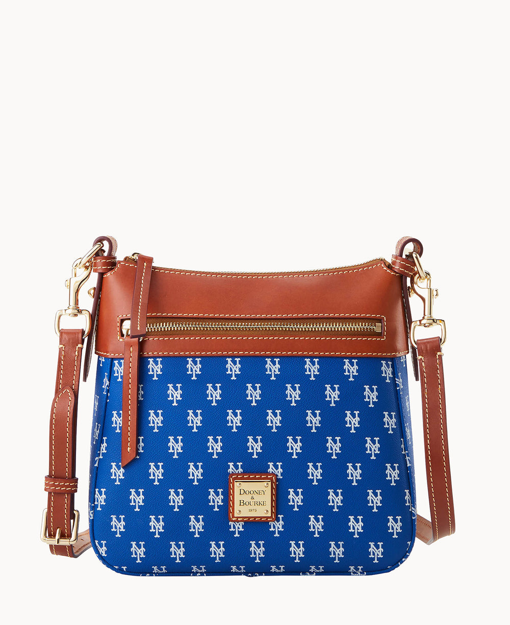A blue crossbody bag with an all-over white New York Mets logo pattern, brown leather trim, gold-tone hardware, front zipper pocket, and an adjustable brown strap. The bag also features a Dooney & Bourke label on the front.