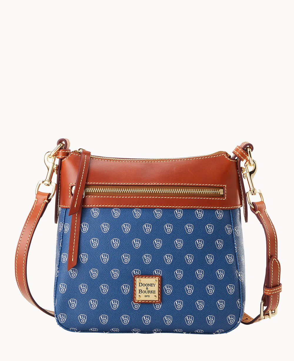 A blue Dooney & Bourke crossbody bag with a brown leather strap and top trim, gold-tone zipper on the front, and a repeating white DB logo pattern on the body.