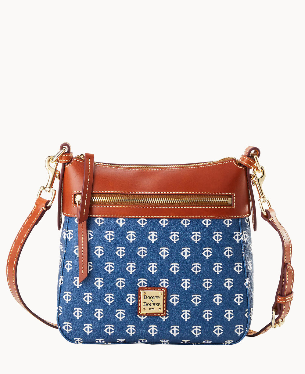 A blue and brown crossbody handbag with a gold zipper, leather strap, and white monogram pattern. The bag features a small gold Dooney & Bourke logo plate on the front.