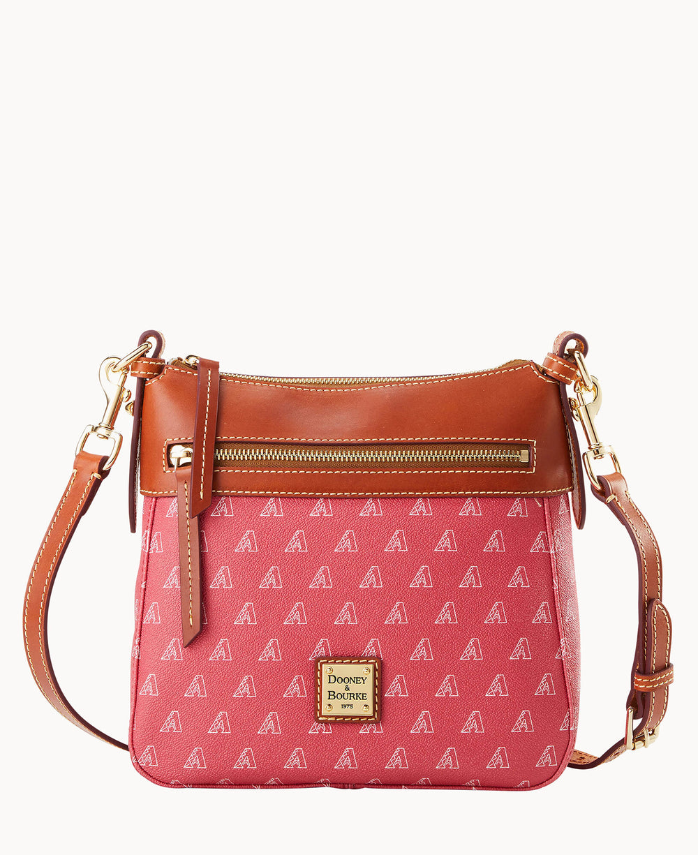 A pink Dooney & Bourke crossbody bag with brown leather trim, a front zipper pocket, gold hardware, adjustable strap, and small repeating â€œAâ€ patterns. A gold Dooney & Bourke logo plaque is on the front.