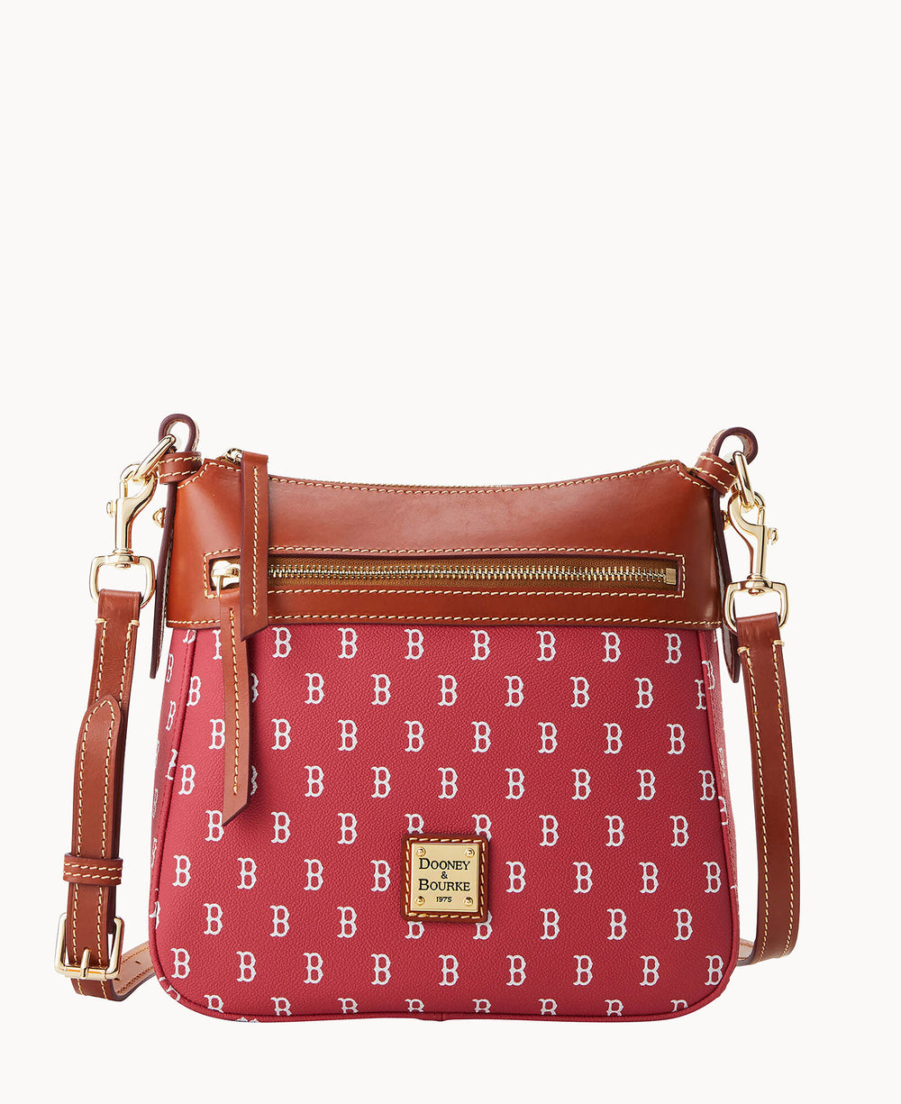 A red crossbody bag with a repeating white DB pattern, brown leather trim, gold hardware, front zipper pocket, and a gold â€œDooney & Bourkeâ€ logo plate on the front.