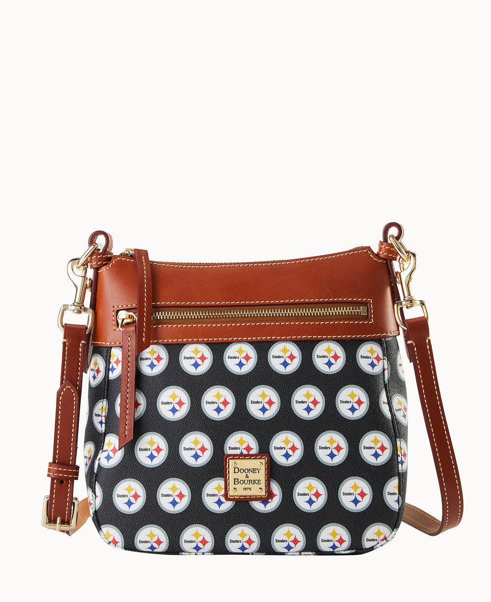 A crossbody purse with a brown leather top and strap, gold hardware, front zipper, and a black body covered with repeating Pittsburgh Steelers logos. A Dooney & Bourke label is on the front.