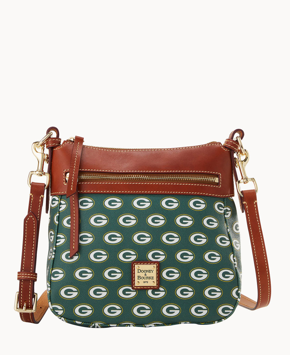 A small crossbody bag with brown leather accents and a green body featuring a repeating Green Bay Packers G logo pattern. The front has a zipper pocket and a metal Dooney & Bourke label.