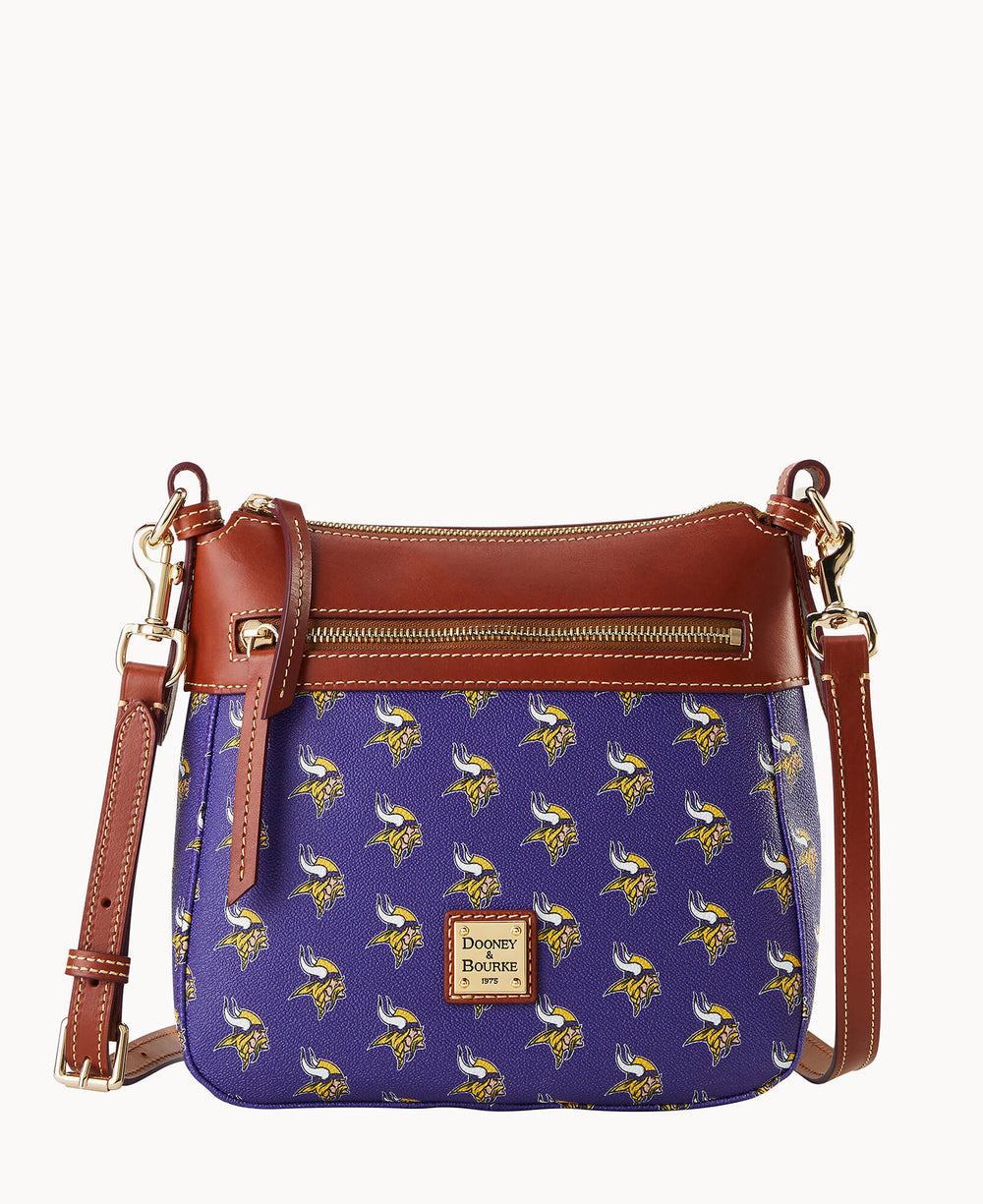 A purple crossbody bag with brown leather accents, gold hardware, and a repeating pattern of Minnesota Vikings logos. The bag has a front zipper pocket and an adjustable strap.