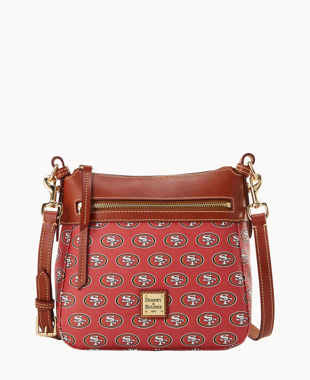 A red Dooney & Bourke crossbody bag with brown leather trim, gold hardware, and an all-over pattern of the San Francisco 49ers logo. The bag has a front zip pocket and adjustable strap.