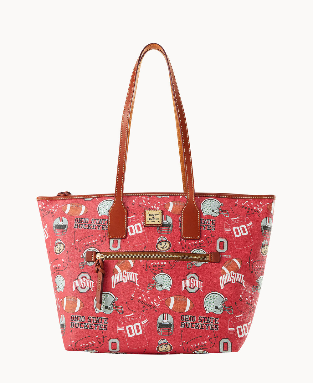A red tote bag with brown handles featuring Ohio State Buckeyes logos, football helmets, footballs, and related graphics. The bag has a front zipper pocket and gold-tone hardware.