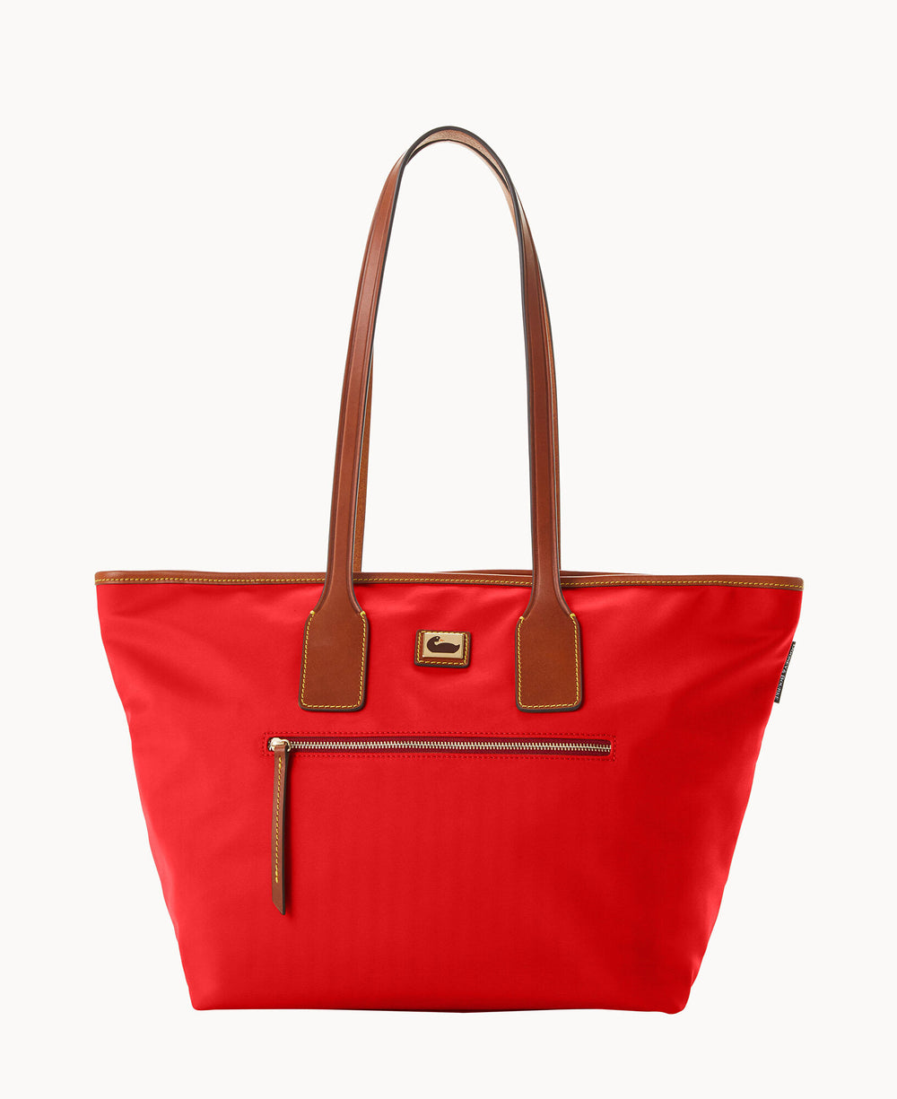 A bright red tote bag with brown leather handles and trim, a front zippered pocket, and a small rectangular logo patch in the center near the top.